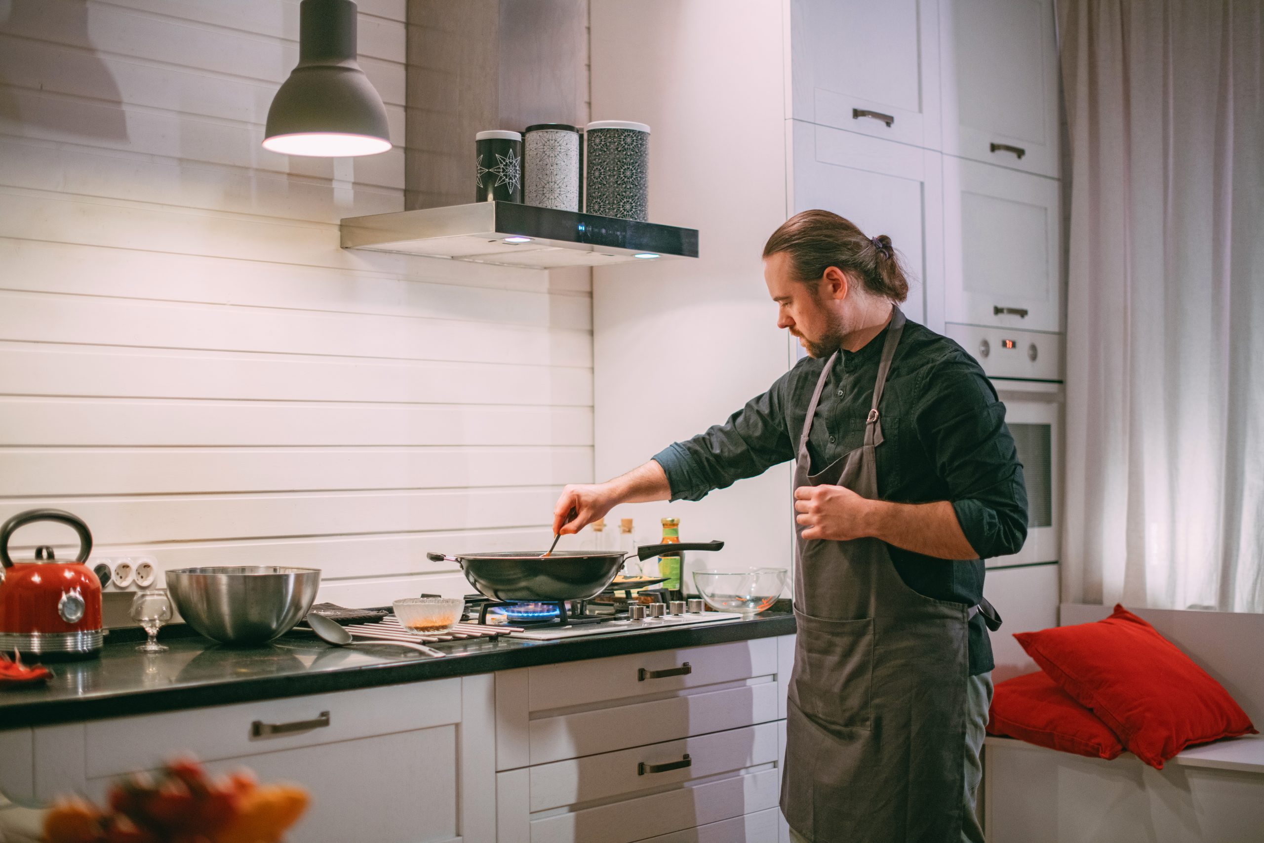 Mann kocht am Gasherd Ein Mann kocht etwas auf seinem Gasherd in seiner hellen Küche.